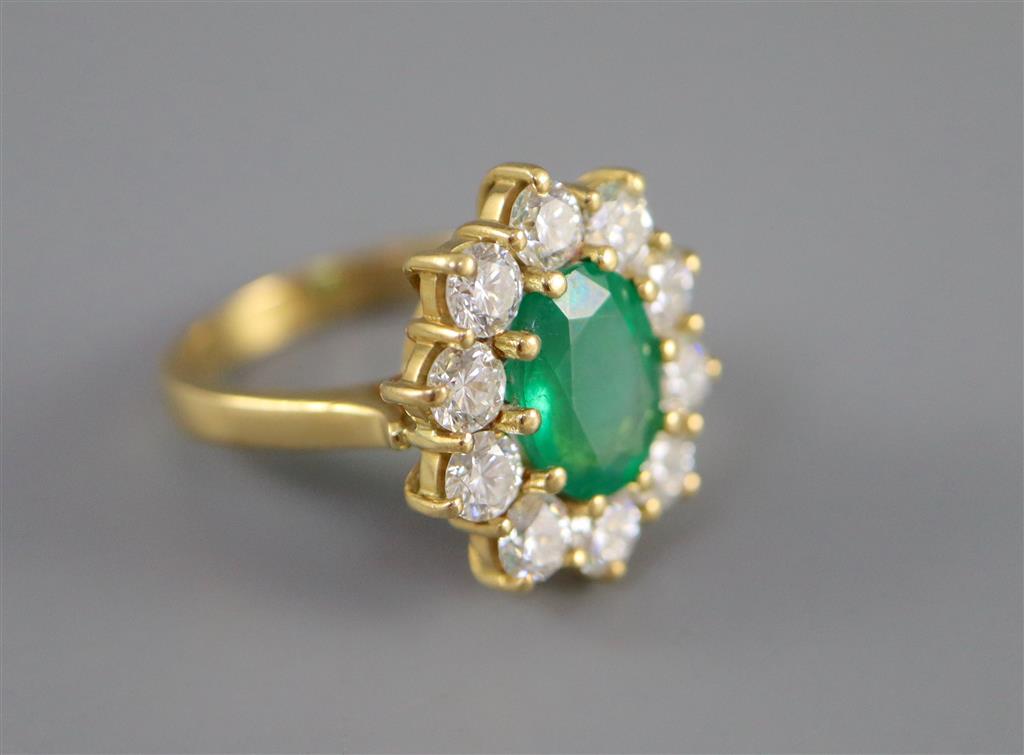 A modern 18ct gold, emerald and diamond oval cluster ring,
